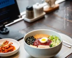 비빔 칼국수를 식당의 테이블에 올리고 자연광으로 촬영한 음식 사진. 푸드그래퍼 울프 케이의 사진 촬영본.